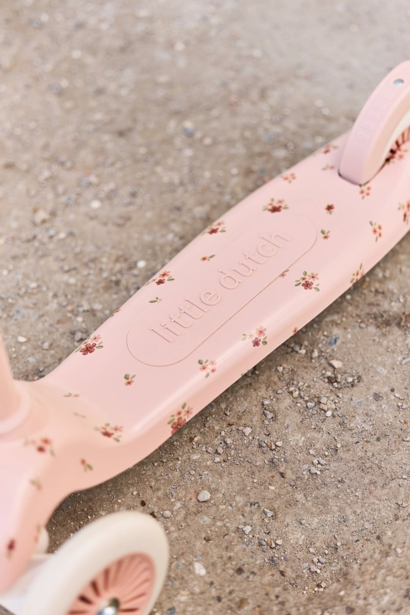 Pink scooter with floral pattern on a sandy surface