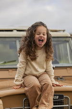 Child sitting on a vintage vehicle with a joyful expression